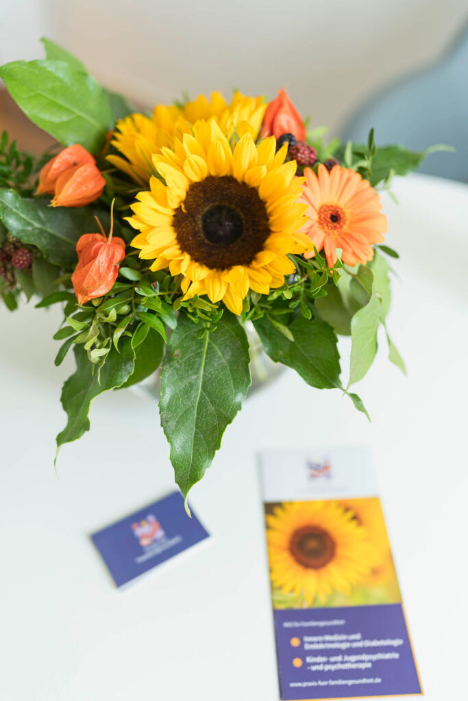 Aufnahme einer Vase im Wartezimmer, neben der Visitenkarten der Praxis aufgestellt liegen