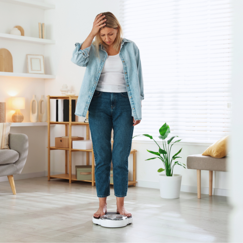 Frau steht auf der Waage und fasst sich geschockt an den Kopf
